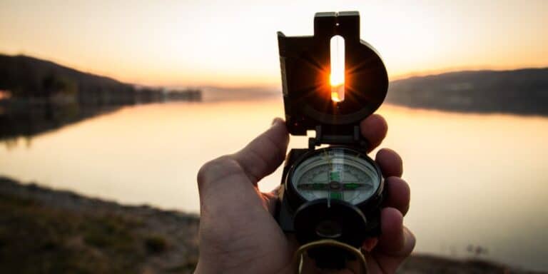 A person holding up a compass towards the sun to help guide them.