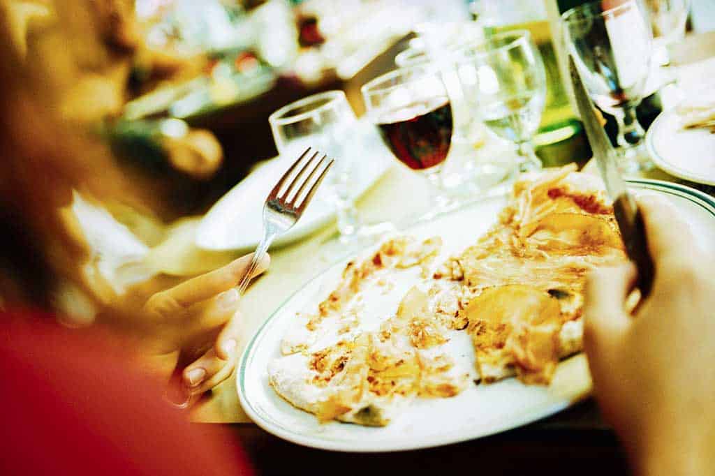 Pictures of woman eating pizza with wine at a restaurant.